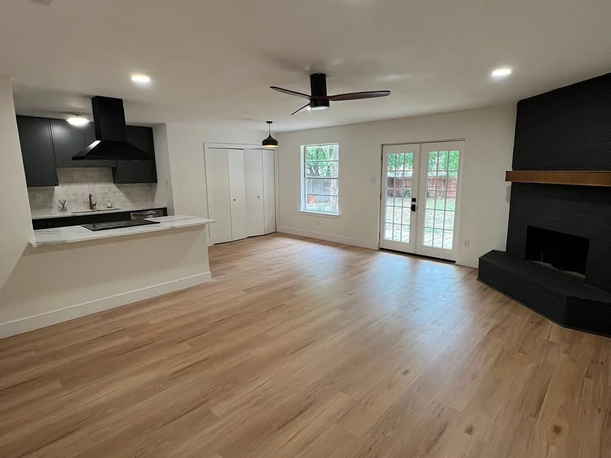 Open plan living and kitchen with continuous wide plank flooring and a black tile fireplace
